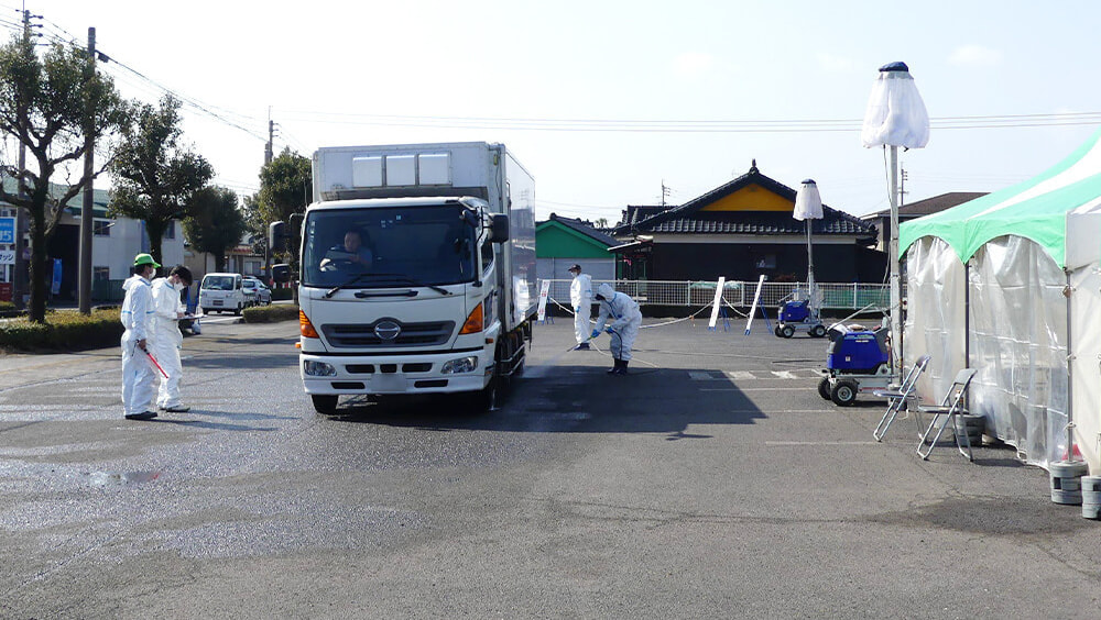 緊急防疫業務として大型車に消毒作業を行っている写真